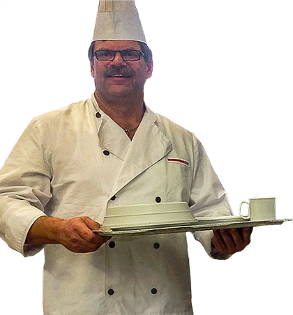 Mann mit Kochmütze und Kochjacke trägt ein Tablett mit Küchenutensilien